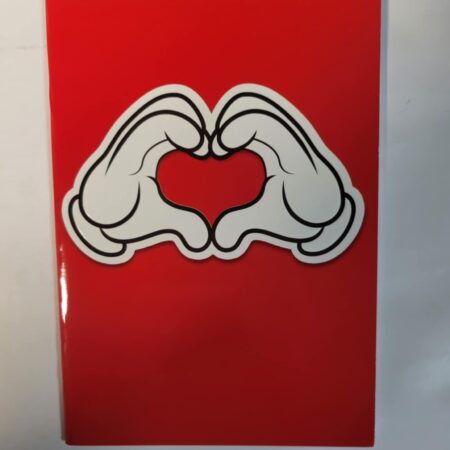 Przedstawiony czerwony zeszyt, dłonie ułożone tworząc serce